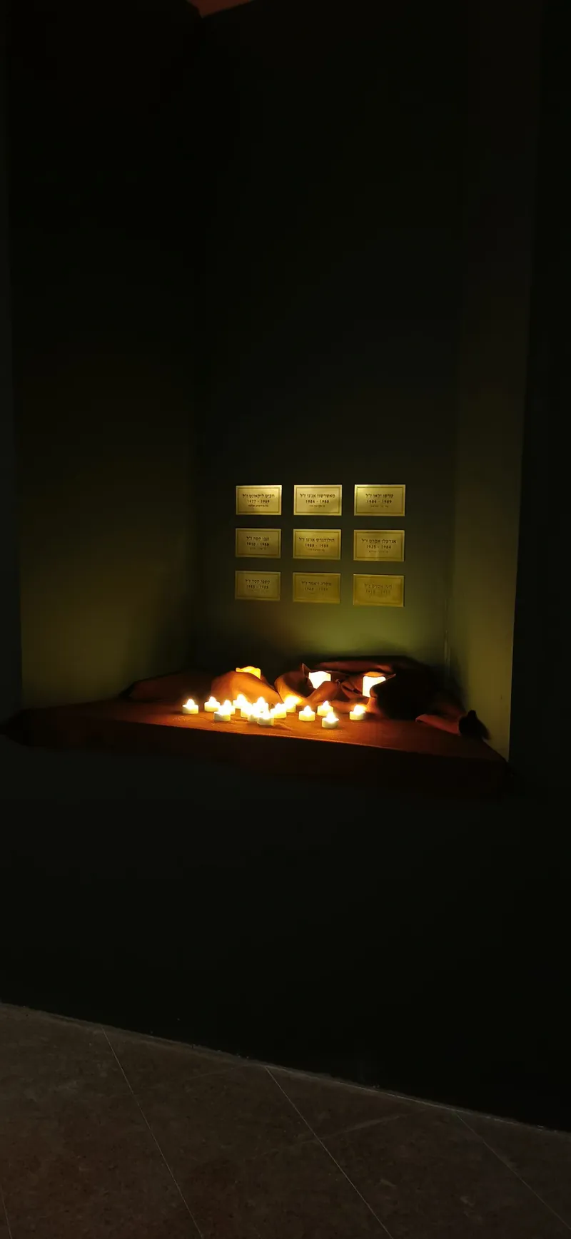 Candlelit memorial niche with name plaques in a Shidrah Studio memorial room