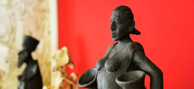 Sculpted terracotta figure set against a red heritage-room wall